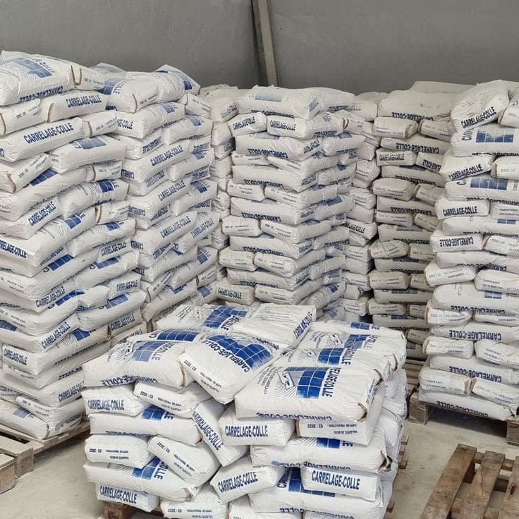 Warehouse pallets stacked with sacks of Carrelage-Colle tile adhesive.
