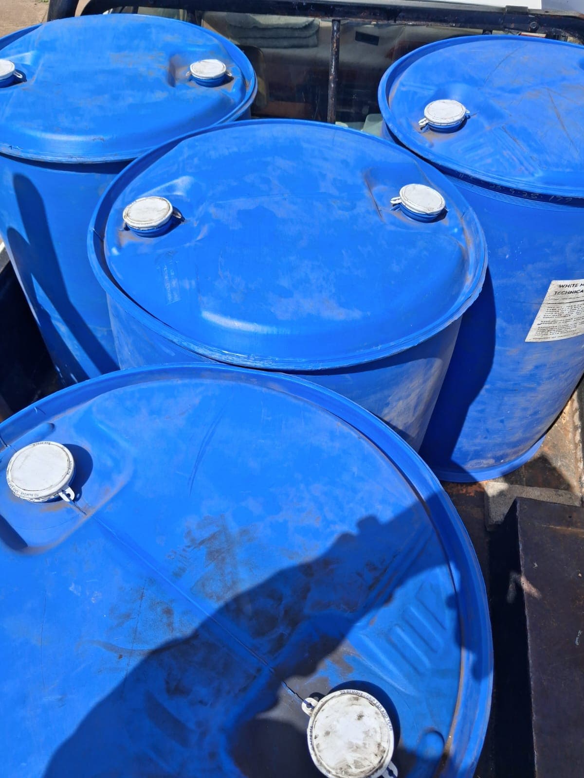 Blue 200-litre plastic drums stacked in a chemical store.